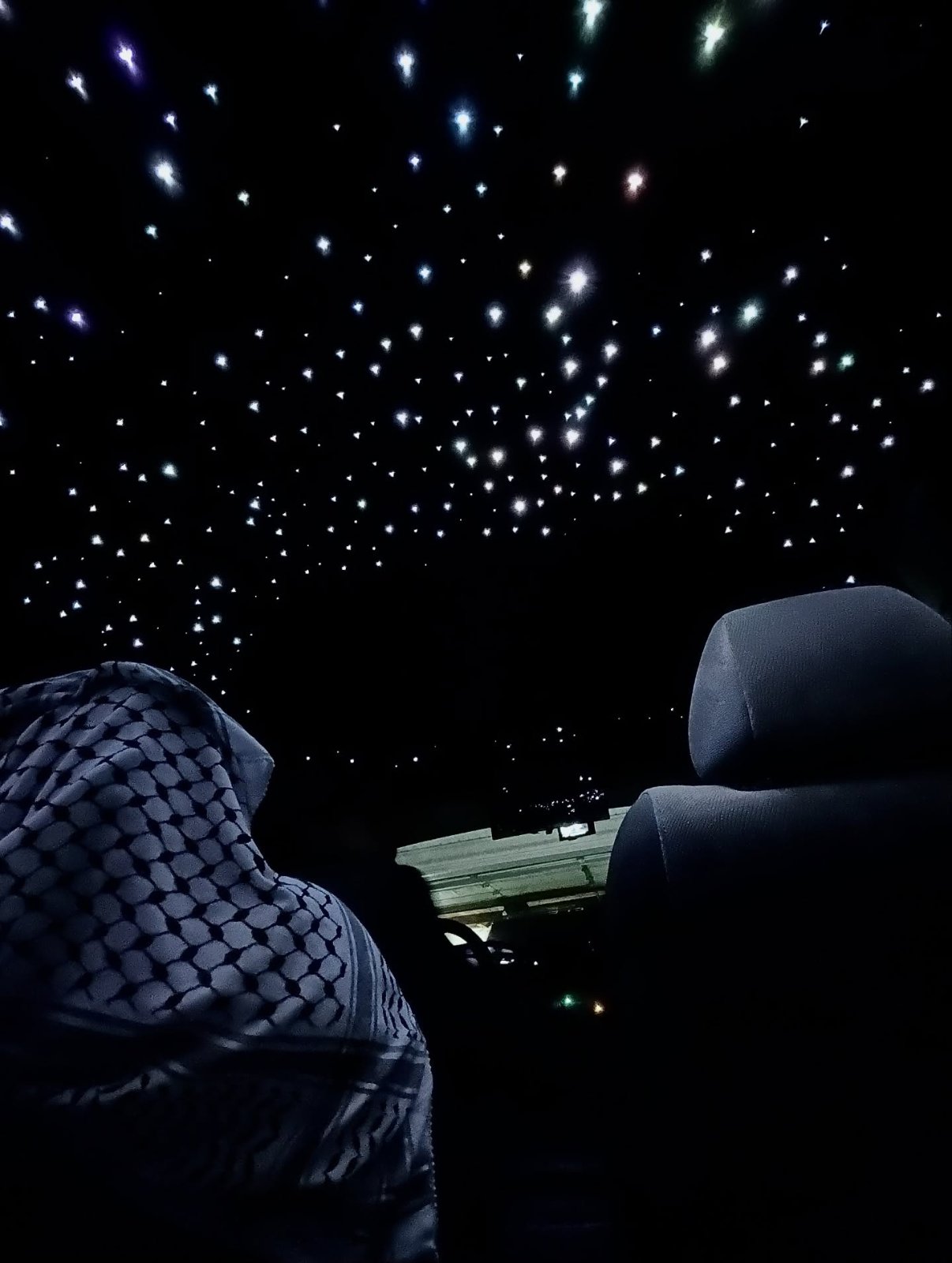 Fiber-optic starlight headliner glowing across a car ceiling at night